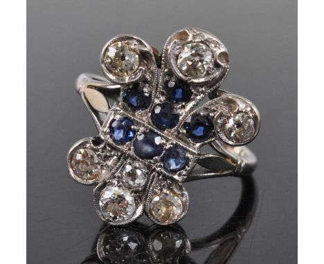 A white metal 'fleur de lys' sapphire and diamond cluster ring, featuring a centre section of seven round faceted sapphires w