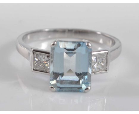 A white metal, aquamarine and diamond three stone ring, comprising a centre rectangular cut aquamarine in four claw setting, 