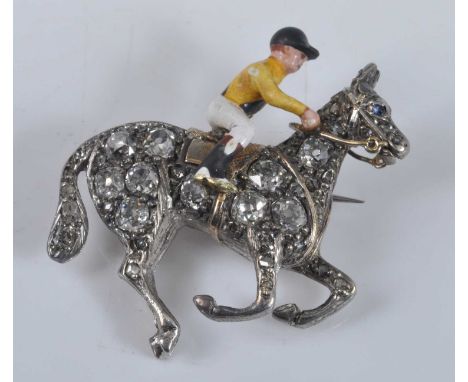 A yellow and white metal horse and jockey brooch, comprising an enamel jockey riding a galloping horse set with 48 Old Europe