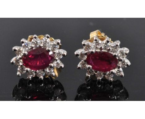 A pair of 18ct yellow and white gold, ruby and diamond oval cluster earrings, each featuring a centre oval faceted ruby withi