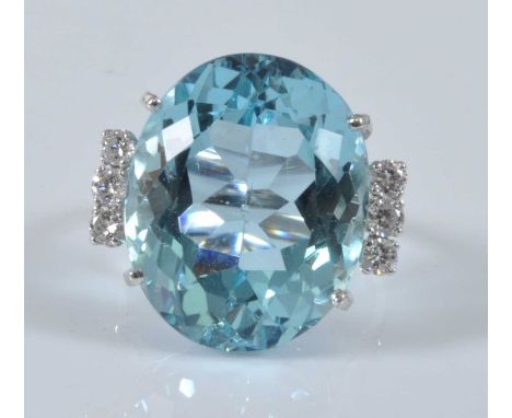 A white metal, aquamarine and diamond ring, comprising a centre oval aquamarine in a four claw setting flanked by three round