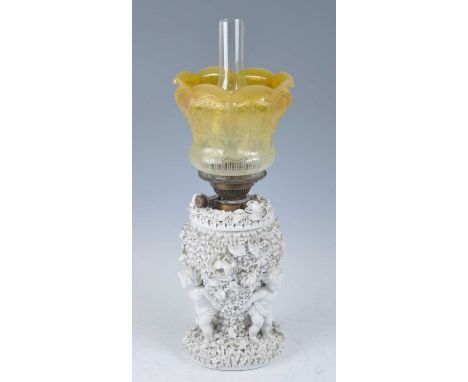 A 19th century Sitzendorf blanc de chine porcelain oil lamp, the acid etched amber tinted glass shade above a heavily floral 