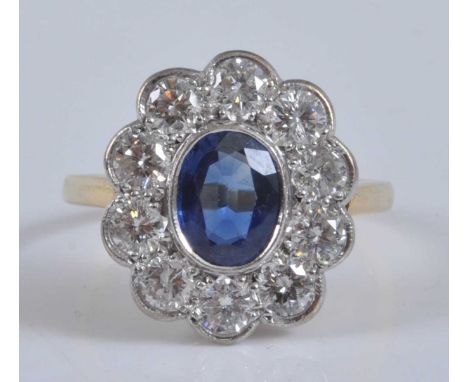A yellow and white metal, sapphire and diamond oval cluster ring, featuring a centre oval sapphire within a border of ten rou