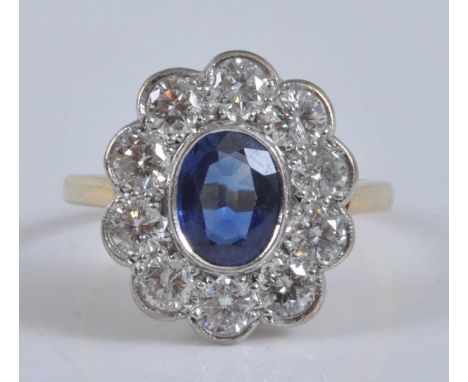 A yellow and white metal, sapphire and diamond oval cluster ring, featuring a centre oval sapphire within a border of ten rou