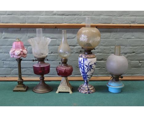 Six oil lamps in brass cast iron and pottery with ruby glass reservoirs, shades and globes