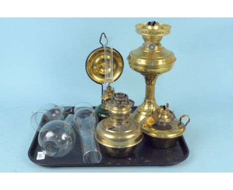 A brass base oil lamp together with two brass reserves, a green glass storm lamp and three funnels