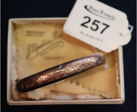 A 9ct gold hinged engraved bangle. (B.P. 24% incl. VAT) CONDITION REPORT: 12g