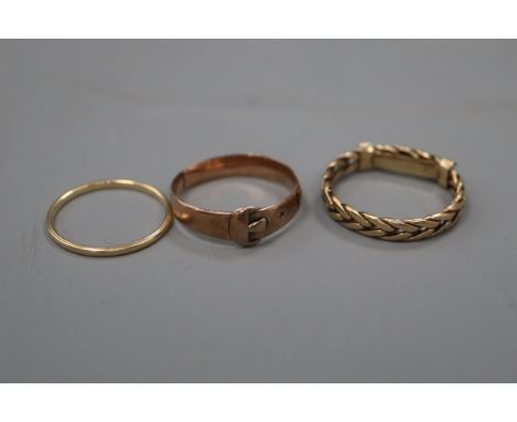 A 14k yellow metal band and two other yellow metal rings including a buckle ring.