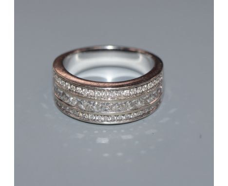 A modern 750 white metal and three row round and princess cut diamond half hoop ring, size O.