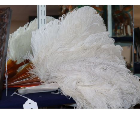 Two white ostrich feather fans, one with gold-monogrammed blond faux-tortoiseshell guard sticks and handle, the other with mo