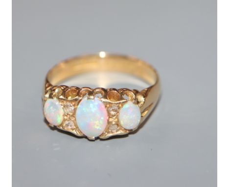 A George V 18ct gold, three stone opal and diamond chip set dress ring, size O.