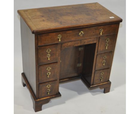 A 19th century walnut kneehole desk in Georgian style, with feather banded top, drawers and cupboards under and bracket feet,