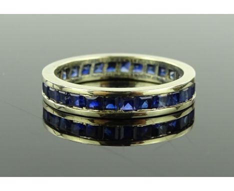 An unmarked white metal sapphire eternity ring, setting height 3.9mm, size R, 3.7g.