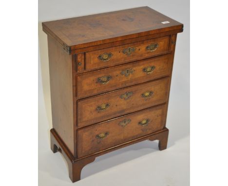 An early 20th century reproduction walnut chest of drawers of small size with feather banded foldover top and bracket feet, w