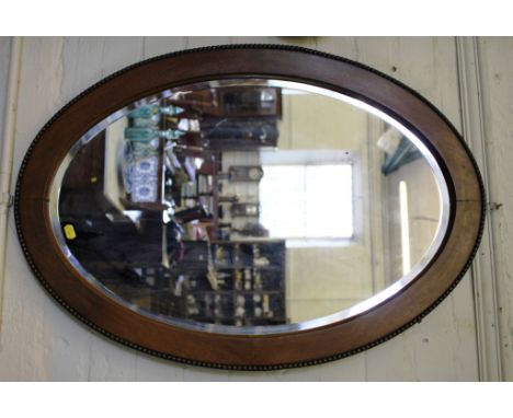 A walnut framed oval mirror, with bevelled plate, 85cm high