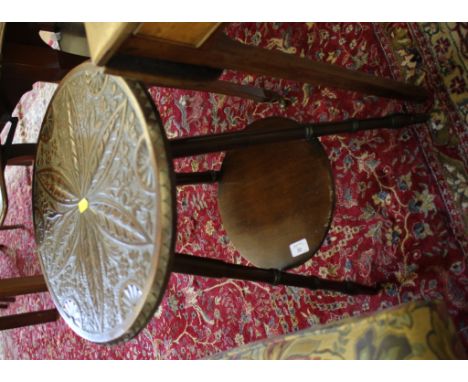 A carved wood tripod table, the circular top carved with flowers and lunettes on turned legs joined by an undershelf, 40cm di