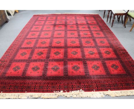 A machine made Persian style fringed carpet on red ground, 387cm by 273cm