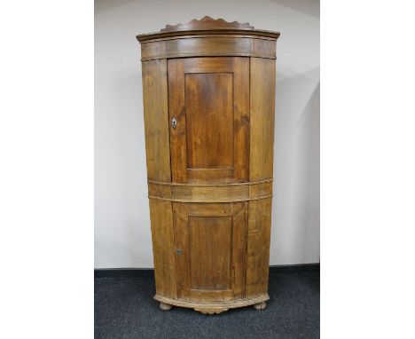 A 19th century continental pine bow fronted double corner cabinet 