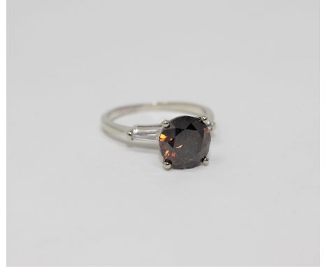 A platinum diamond solitaire ring, the cognac-brown brilliant-cut diamond weighing 3.05 carats, the shoulders set with two ba