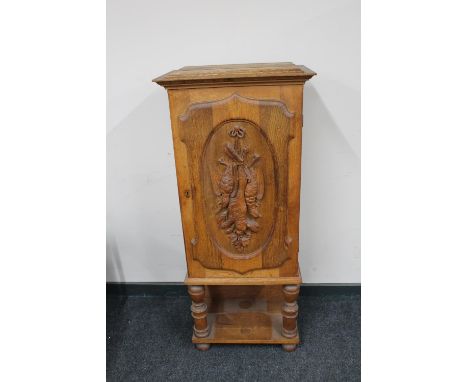 A continental oak hunting cabinet on raised legs with carved panel door 