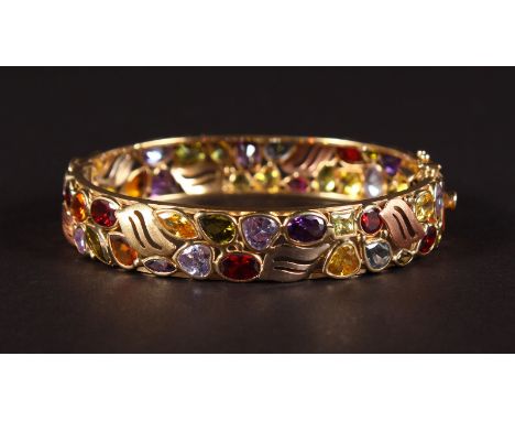 A 14CT YELLOW GOLD MULTI GEMSTONE  BANGLE, set with garnets, topaz, tourmaline, peridot and amethyst.