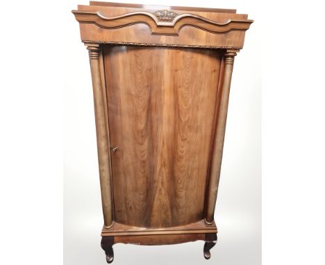 An early 20th century continental bow-front single door cabinet with pillar supports, 85 cm x 44 cm x 167 cm 