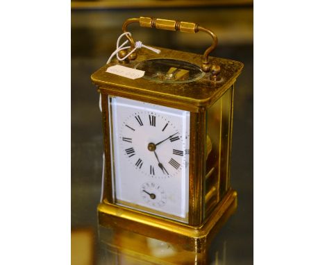 A brass carriage clock, with loop handle, projected moulded cornice over enamelled face, Roman numerals, subsidiary dial, rai