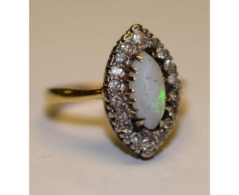 An 18ct gold and platinum opal and diamond dress ring, the central opal surmounted by 18 round cut diamonds set in a marquis 