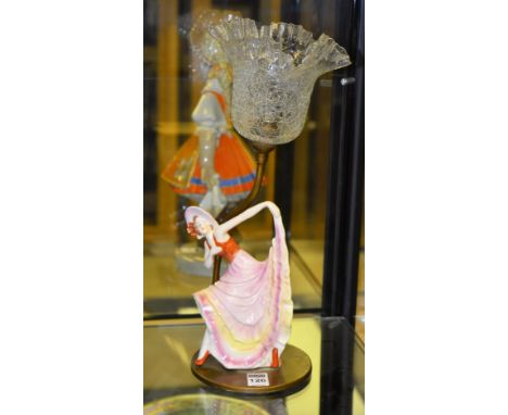 An Art Deco porcelain statuette table lamp, modelled as a lady with flowing dress, crackle glass shade, raised on a circular 