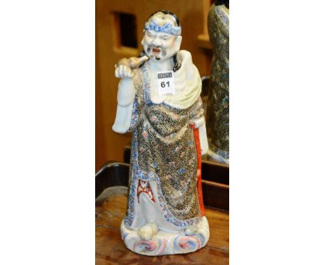 A Japanese porcelain figure, depicting an older man holding a vessel in right hand and orange glazed cane in left hand, weari