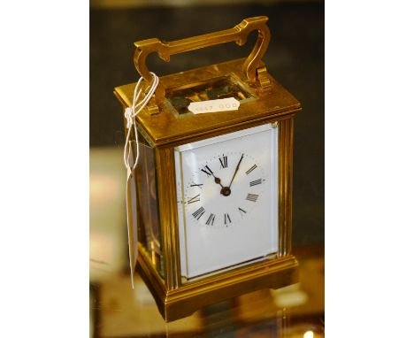 A brass carriage clock, with loop handle over moulded cornice, enamelled face and Roman numerals, raised on bracket feet, sta