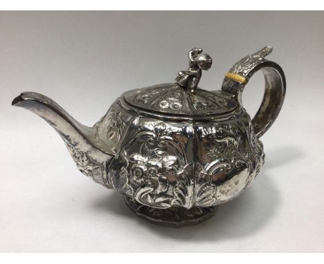 George IV silver teapot of compressed globular form with vertical panelled sides, embossed with scrolling foliage and cartouc