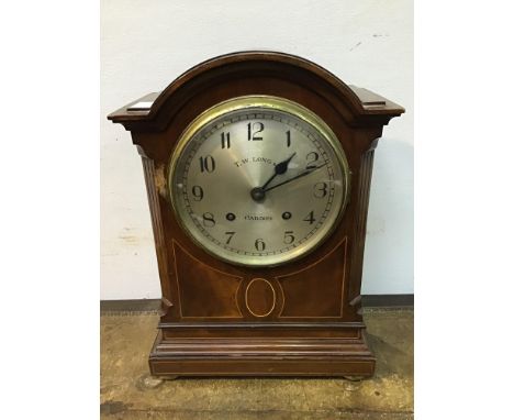 A late 19th / early 20th century mahogany inlaid eight day mantel clock, with arched top, silvered dial with Arabic numerals,