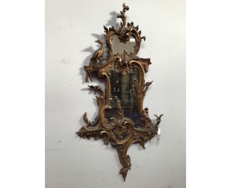 A 19th century Chippendale style finely carved giltwood rococo wall mirror, with scrolling foliage and surmounted with a ho h