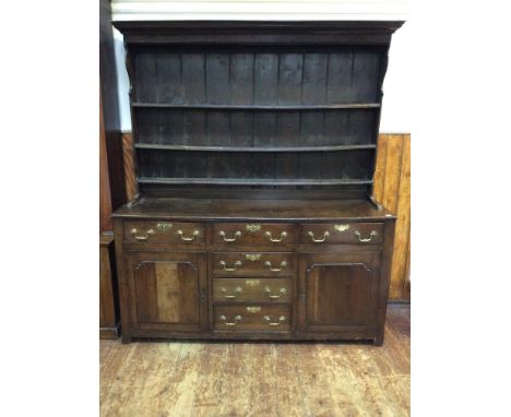 An 18th century and later oak dresser, with shelved and planked back, the base with three frieze drawers above a central bank
