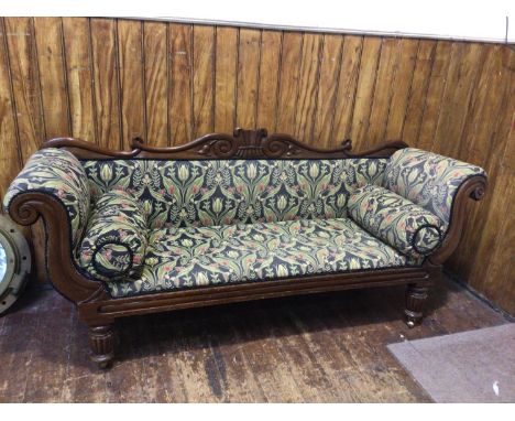 A Victorian stained mahogany sofa, with shaped carved crest rail, and scrolled arms, on reeded front supports to brass sabot 