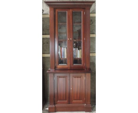 A matching pair of tall mahogany Bookcases, of narrow proportions, each with moulded cornice over two glazed doors and two pa