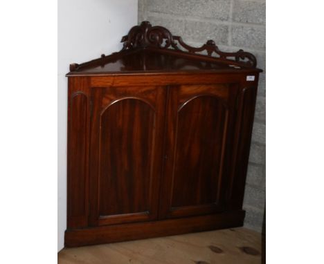 An unusual mahogany Corner Cabinet, of low proportions with pierced decorated back over arched panel doors on plinth base. (1