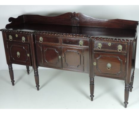 An early 19th Century mahogany inverted breakfront Sideboard, with shaped back, and rectangular top with rope edge, over thre