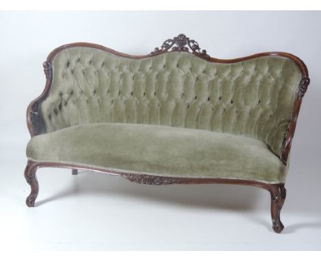 An early Victorian period walnut deep buttoned Settee, the back with scrolled and pierced carved rail centred by fruit, and w