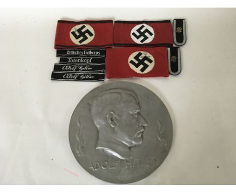 A group of German WW2 items to include 3 armbands, some uniform tallies and an enlarged Adolf Hitler side portrait.