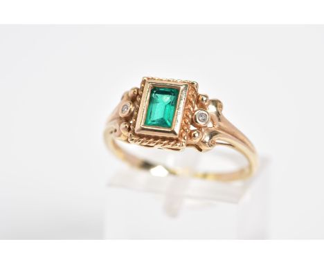 AN EMERALD AND DIAMOND RING, designed with a central rectangle cut emerald within a collet mount and rope twist surround to t