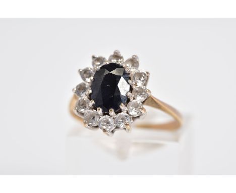 A 9CT GOLD SAPPHIRE CLUSTER RING, the raised cluster designed with a claw set oval cut sapphire and circular cut cubic zircon