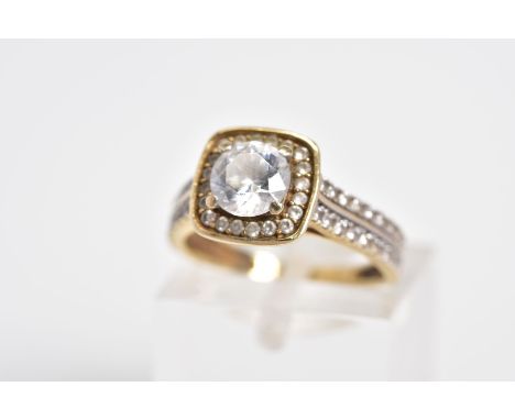 A 9CT GOLD CUBIC ZIRCONIA SET RING, designed with a raised central square panel set with a circular cut cubic zirconia and cu