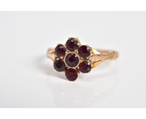 A GARNET SET CLUSTER RING, the yellow metal ring designed as a cluster set with seven circular cut garnets, to the detailed s