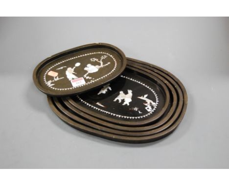 A graduated set of five black lacquered and mother of pearl inlaid trays, largest 34x26cm