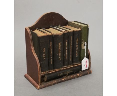 A small Victorian leather clad book trough containing various miniature leather bound books