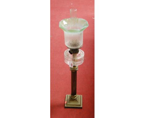 A Victorian oil lamp, having a frilled etched green tinted glass shade above a clear glass font, on brass column and stepped 