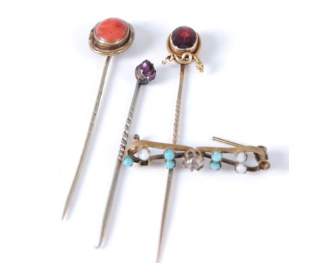 A circa 1900 yellow metal garnet set stick pin, with entwined snake detail; together with a coral set and an amethyst example