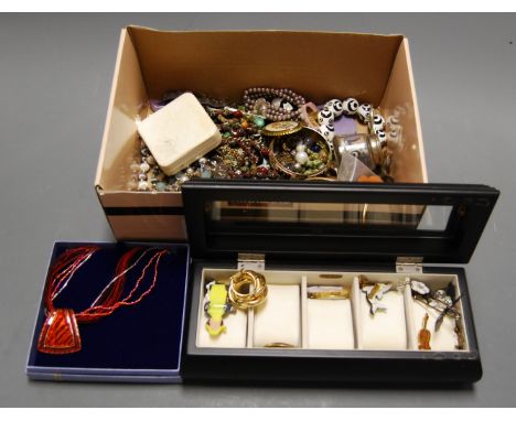 A box of miscellaneous costume jewellery to include various beaded necklaces, silver plated bangle, enamelled lapel badges et